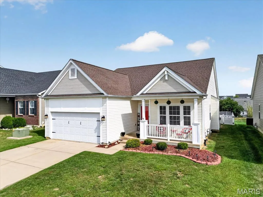 Single-story residence featuring light-colored siding, an attached two-car garage, and a covered front porch with white railings — 2031 Preston Woods Parkway, Lake St. Louis, MO 63367