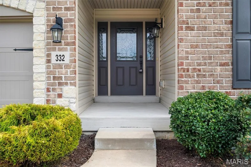 Brick and stone veneer exterior with decorative entry door, sidelights, and exterior lighting fixtures — 332 Mystic Brook Drive, O'Fallon, MO 63366