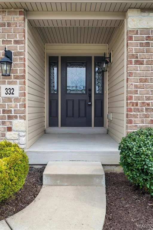 Entry features a dark paneled door with decorative glass inserts, flanked by sidelights — 332 Mystic Brook Drive, O'Fallon, MO 63366