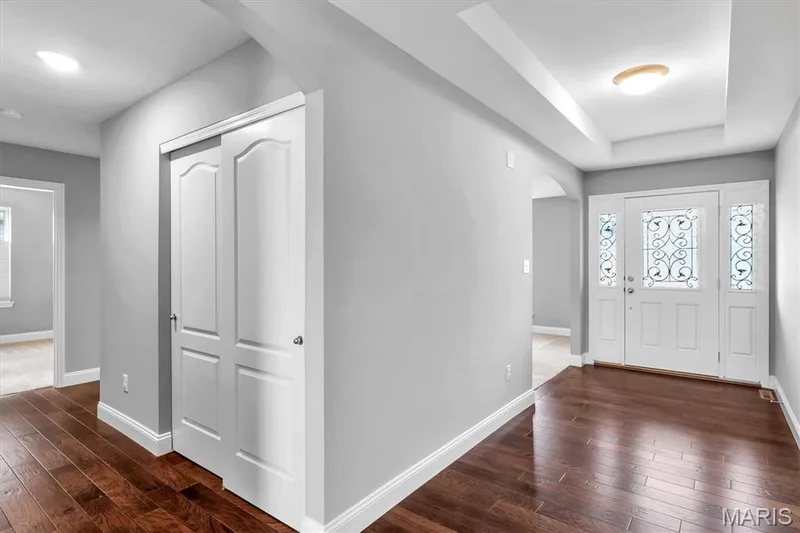 Wood-finish flooring, recessed lighting, double entry doors with decorative glass panels, a tray ceiling, and a bi-fold closet door — 332 Mystic Brook Drive, O'Fallon, MO 63366