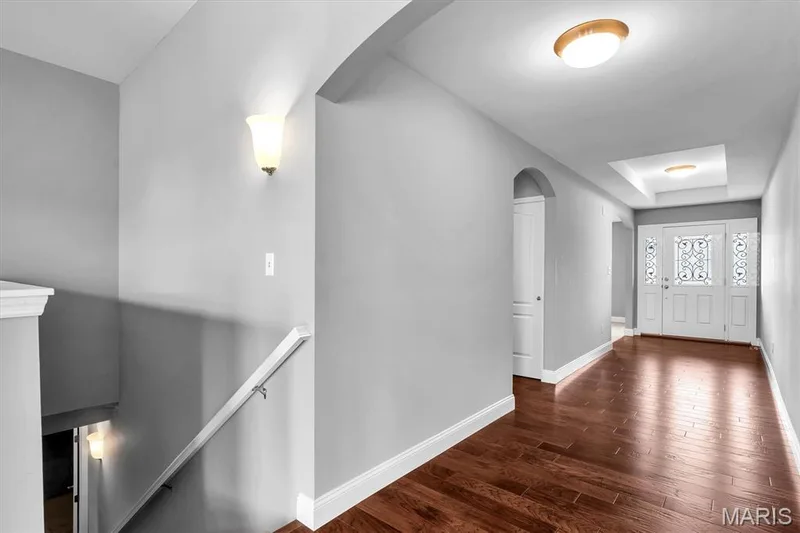 Hardwood flooring, arched doorways, tray ceiling, decorative glass front door, and wall sconces — 332 Mystic Brook Drive, O'Fallon, MO 63366
