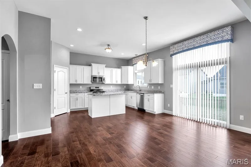 Modern kitchen featuring white cabinetry, stainless steel appliances, a center island, and wood-finish flooring — 332 Mystic Brook Drive, O'Fallon, MO 63366