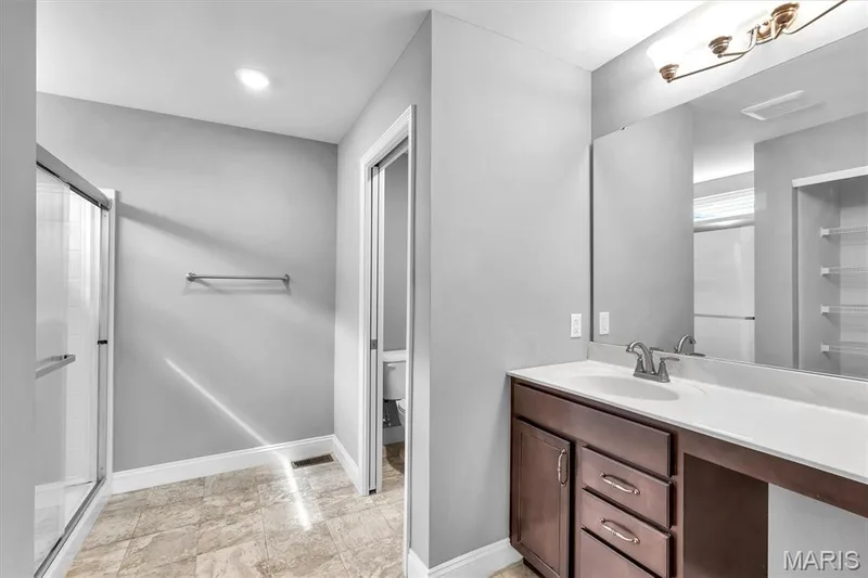 Vanity with integrated sink, dark wood cabinetry, and brushed nickel hardware — 332 Mystic Brook Drive, O'Fallon, MO 63366