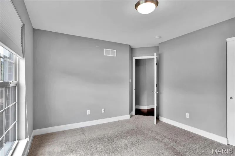 Neutral gray wall paint, textured carpeting, large window with blinds, interior door, and flush mount ceiling light — 332 Mystic Brook Drive, O'Fallon, MO 63366