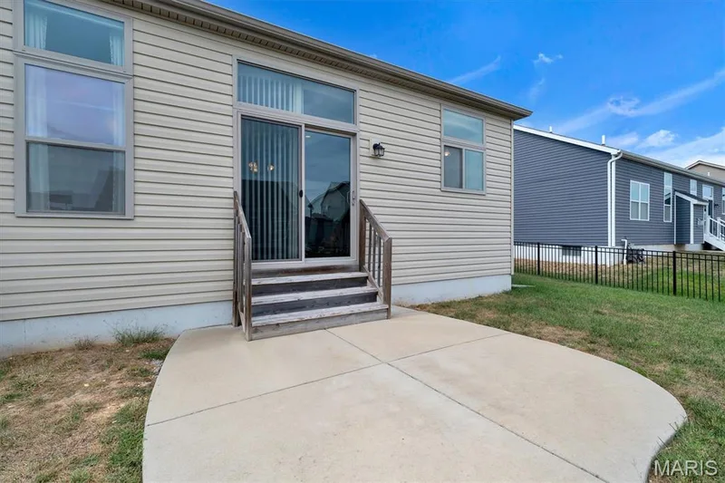 Exterior featuring light-colored horizontal siding, a sliding glass door, and an exterior light fixture — 332 Mystic Brook Drive, O'Fallon, MO 63366