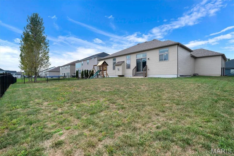 Expansive backyard with a black metal fence, mature tree, and rear siding — 332 Mystic Brook Drive, O'Fallon, MO 63366