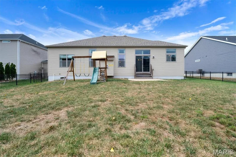 Rear exterior with light-toned siding, a concrete patio, and a shingled roof — 332 Mystic Brook Drive, O'Fallon, MO 63366