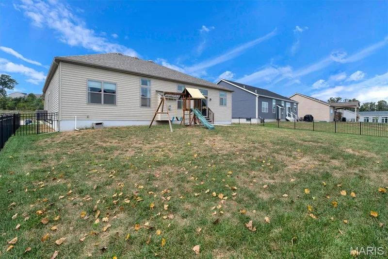 Expansive backyard featuring a partial black metal fence and a beige vinyl-sided exterior — 332 Mystic Brook Drive, O'Fallon, MO 63366