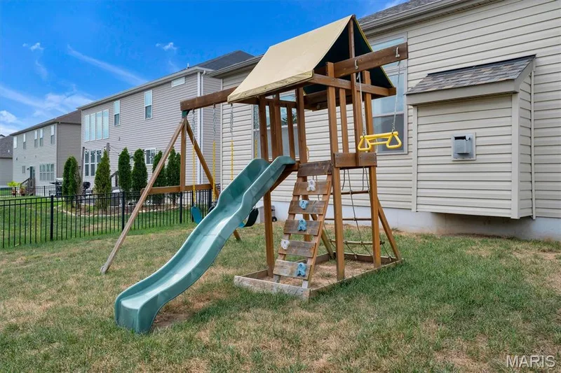 Fenced backyard featuring a wood playset with a slide and swing — 332 Mystic Brook Drive, O'Fallon, MO 63366