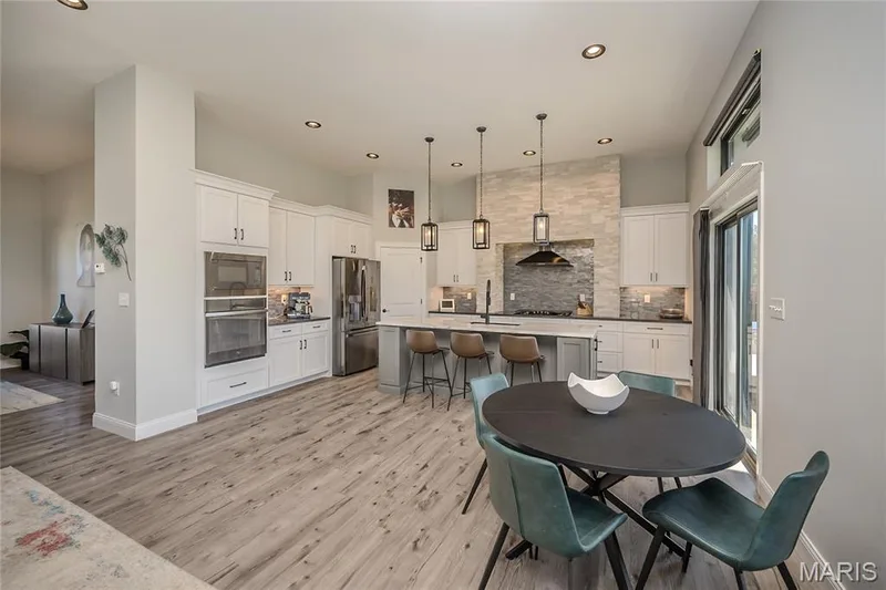 The owner chose sleek craftsman cabinetry in soft white with a clean crown finish that defines the volume of the space.  The pendant lantern lighting has been selected to softly illuminate the endless counters and the magic of this chef's grotto. — 121 Eagle Estates Drive, Lake St. Louis, MO 63367