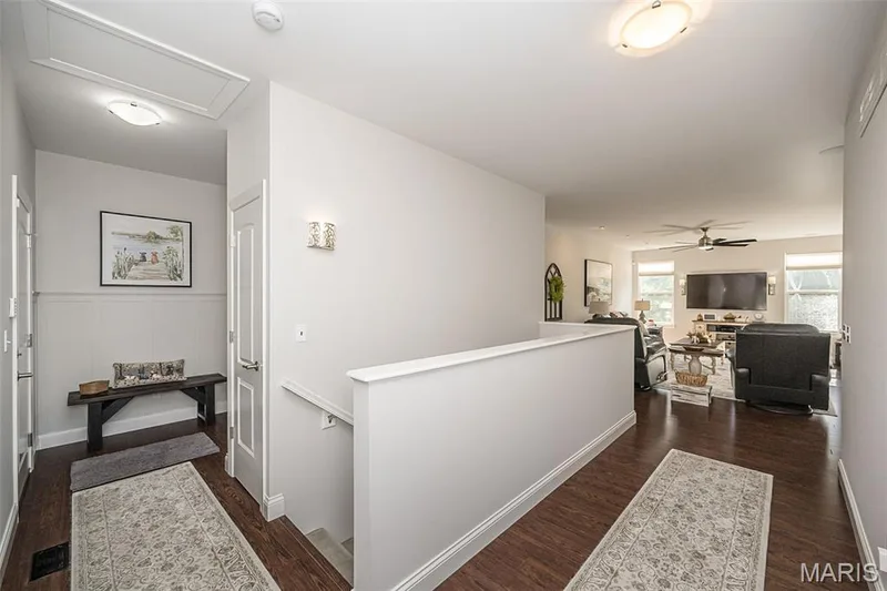 Wood-finish flooring throughout the hallway and living area, featuring a decorative wall sconce — 1509 Woodside Hills Drive, St Peters, MO 63376