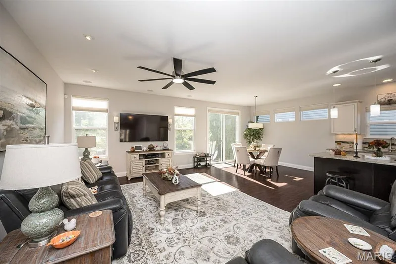 Recessed lighting, dark wood-finish flooring, ceiling fan, sliding glass door, and kitchen island with pendant lighting — 1509 Woodside Hills Drive, St Peters, MO 63376