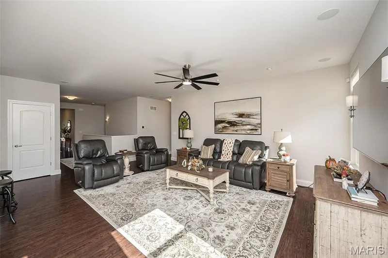Spacious living area featuring wood-finish flooring, a ceiling fan, recessed lighting, and wall sconces — 1509 Woodside Hills Drive, St Peters, MO 63376