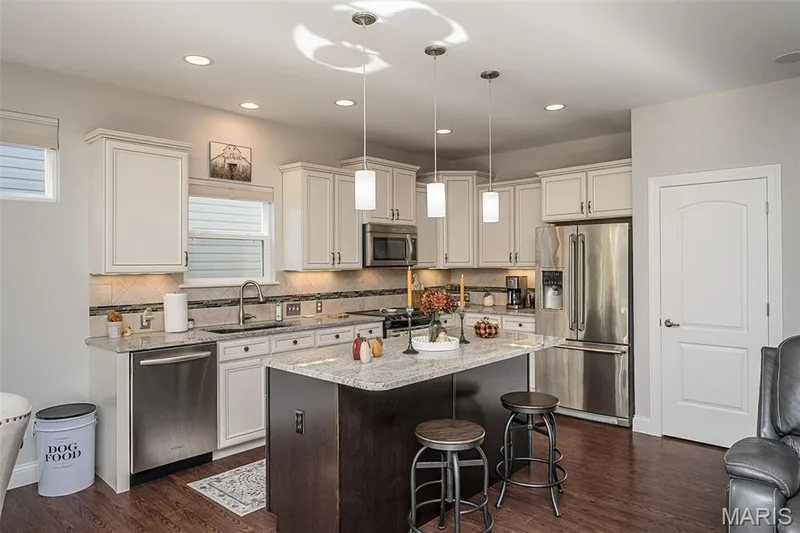 Kitchen featuring white cabinetry, stainless steel appliances, a center island with a stone countertop, and wood-finish flooring — 1509 Woodside Hills Drive, St Peters, MO 63376