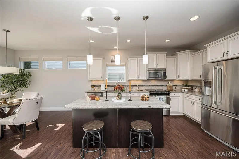 Kitchen featuring white cabinetry, stainless steel appliances, a center island with a light-colored countertop, and wood-finish flooring — 1509 Woodside Hills Drive, St Peters, MO 63376