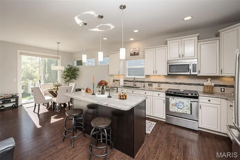 Kitchen featuring white cabinetry, granite countertops, stainless steel appliances, and wood-finish flooring — 1509 Woodside Hills Drive, St Peters, MO 63376