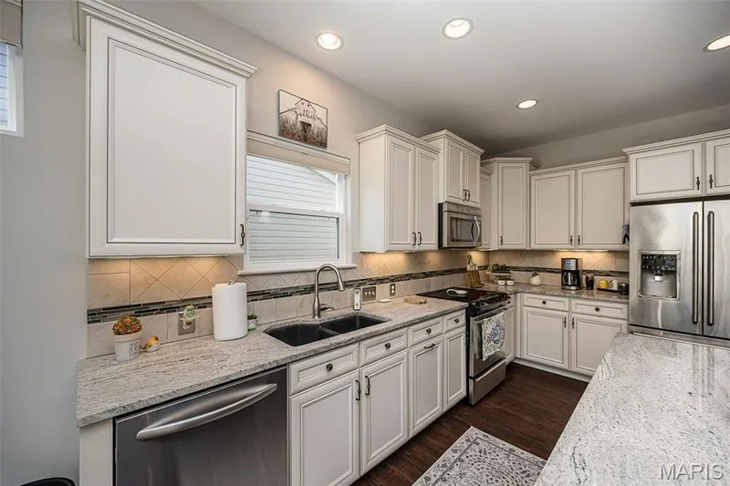 Kitchen featuring white cabinetry, light-toned countertops, a stainless steel dishwasher, a stainless steel double-door refrigerator, and recessed lighting — 1509 Woodside Hills Drive, St Peters, MO 63376