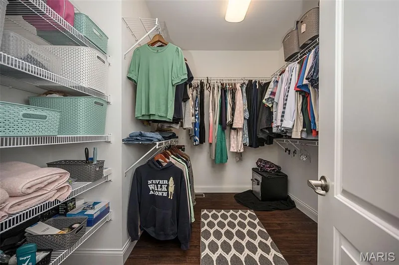 Walk-in closet featuring wire shelving, hanging rods, and dark wood-finish flooring — 1509 Woodside Hills Drive, St Peters, MO 63376