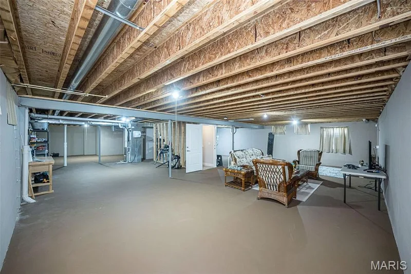 Expansive lower level with painted concrete flooring, exposed ceiling joists, and multiple recessed light fixtures — 1509 Woodside Hills Drive, St Peters, MO 63376