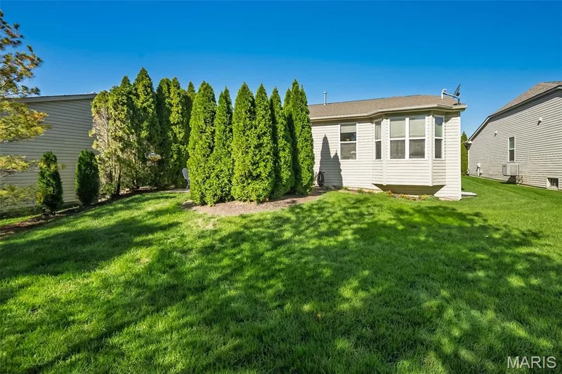 Expansive green lawn with mature evergreen plantings and a bay window extension — 1509 Woodside Hills Drive, St Peters, MO 63376