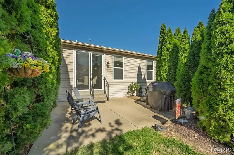 Rear patio with concrete surface, direct exterior access, and surrounding manicured trees — 1509 Woodside Hills Drive, St Peters, MO 63376
