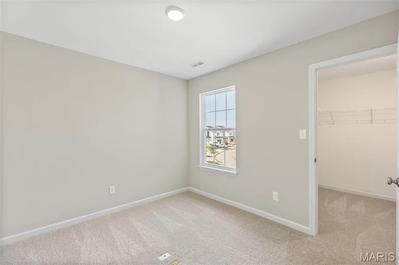 Unfurnished bedroom featuring light colored carpet, a walk in closet, and a closet — 2 Burlington at Fairmount Grove, St Peters, MO 63376