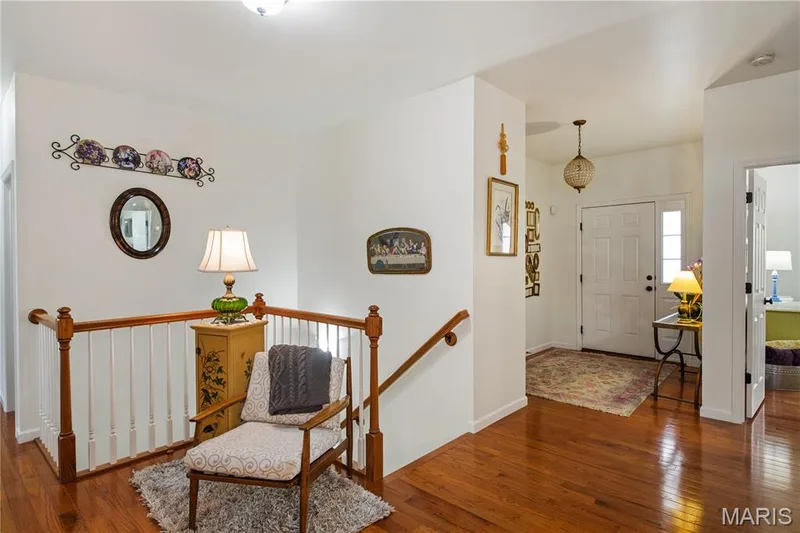 Hardwood flooring, painted white walls, white paneled doors, staircase with wood handrails and white balusters, and a front entry door view — 149 Amiot Court, Chesterfield, MO 63146