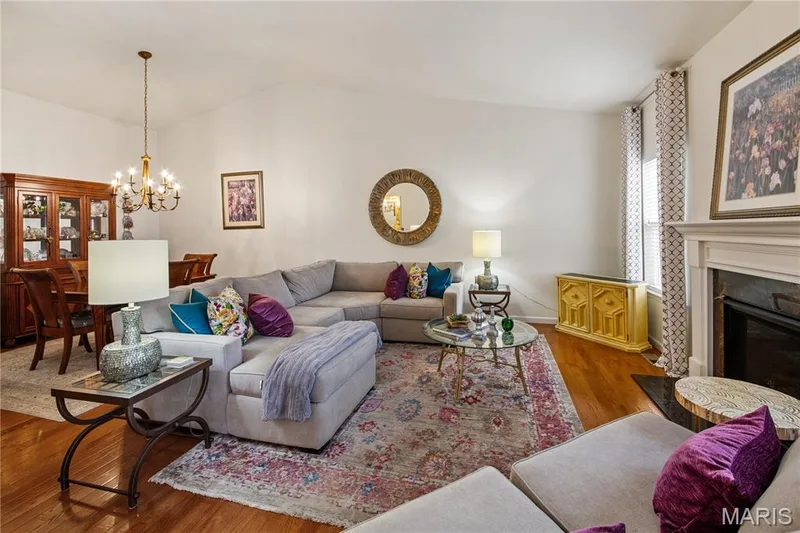 Vaulted ceiling, wood-finish flooring, fireplace with mantel, window with drapery, and a chandelier in the dining area — 149 Amiot Court, Chesterfield, MO 63146