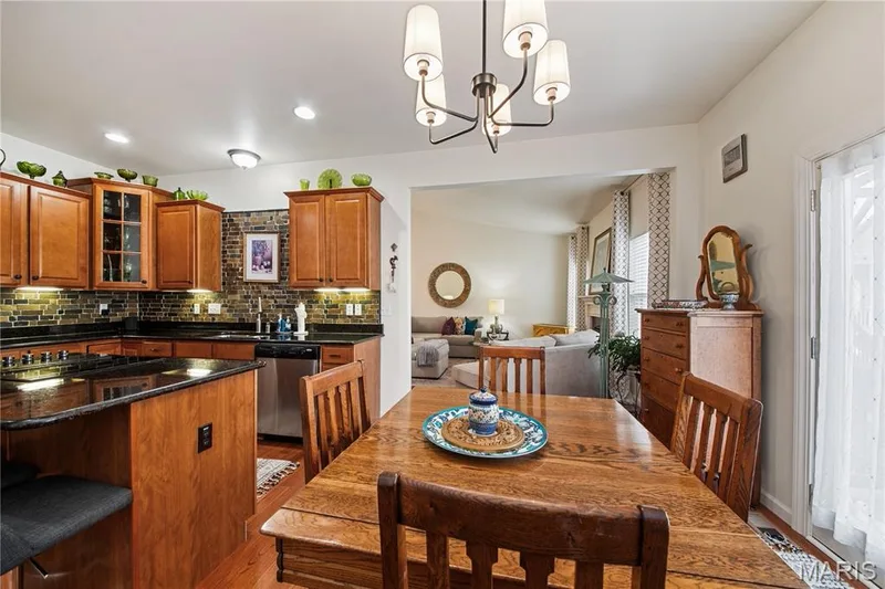 Kitchen featuring wood cabinetry, black countertops, a mosaic tile backsplash, and stainless-steel appliances — 149 Amiot Court, Chesterfield, MO 63146