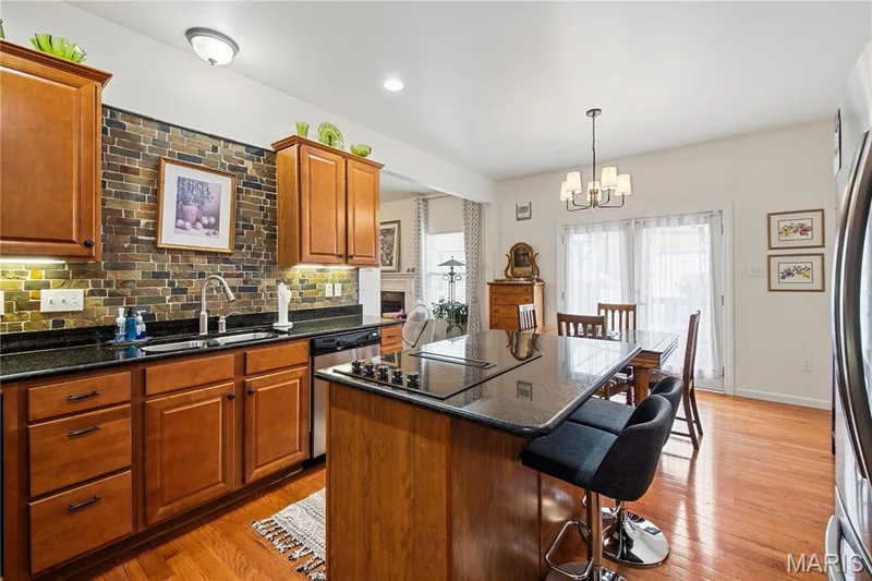 Kitchen featuring wood cabinetry, dark countertops, a tile backsplash, and stainless steel appliances — 149 Amiot Court, Chesterfield, MO 63146