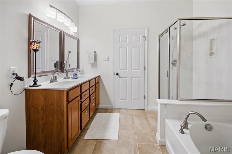 Dual vanity with wood-finish cabinetry, white countertop, and framed mirrors — 149 Amiot Court, Chesterfield, MO 63146