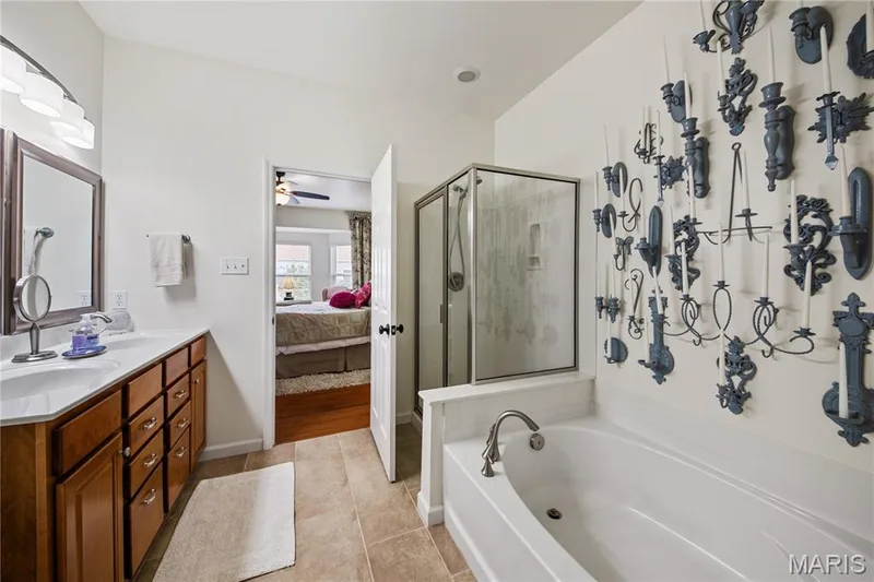 Dual vanity with integrated sinks, framed mirrors, glass-enclosed shower, built-in soaking tub, and tile flooring — 149 Amiot Court, Chesterfield, MO 63146