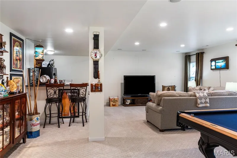Recessed lighting throughout, built-in bar area with seating, carpeting, and a visible window with drapes — 149 Amiot Court, Chesterfield, MO 63146