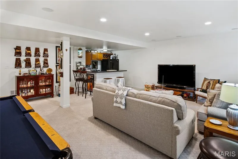 Expansive basement space featuring recessed lighting, a built-in bar with wood-finish cabinetry, a black countertop, and light-colored carpet — 149 Amiot Court, Chesterfield, MO 63146