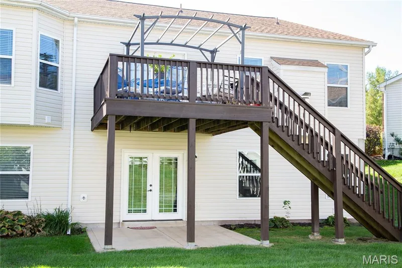 Elevated wood-tone deck with full staircase and railing, two-story exterior with light-toned siding, bay window, and ground-level double glass doors — 149 Amiot Court, Chesterfield, MO 63146