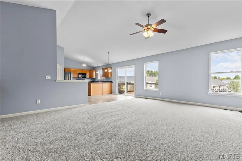 Vaulted ceiling, ceiling fan, carpeted flooring, multiple windows, and a sliding glass door — 521 Cimarron Woods Court, Wentzville, MO 63385