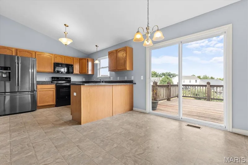 Kitchen featuring wood cabinetry, stainless steel refrigerator, black appliances, dark countertops, and tile flooring — 521 Cimarron Woods Court, Wentzville, MO 63385