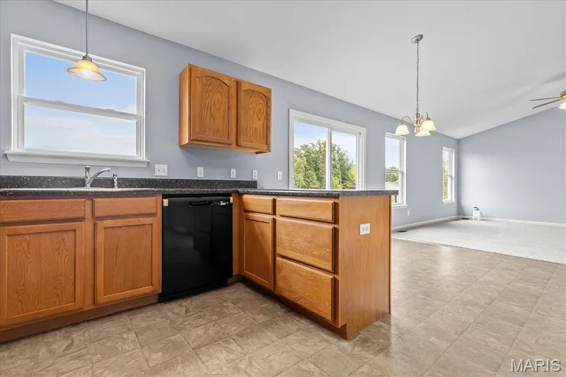 Kitchen with wood cabinetry, dark countertops, a black dishwasher, and tile flooring — 521 Cimarron Woods Court, Wentzville, MO 63385