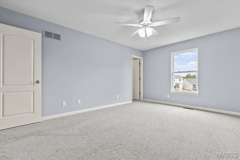 Light blue painted walls, gray carpet, white trim, ceiling fan with integrated lighting, and a single window — 521 Cimarron Woods Court, Wentzville, MO 63385