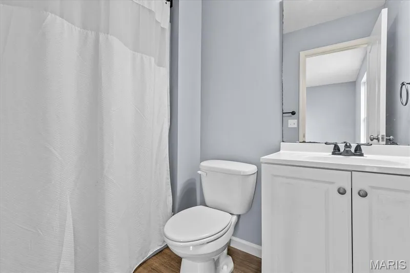 Bathroom featuring wood-finish flooring, white vanity with integrated sink, and dark-toned hardware — 521 Cimarron Woods Court, Wentzville, MO 63385