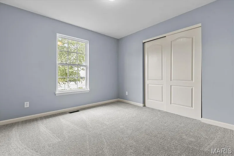 Light gray wall-to-wall carpeting, white bi-fold closet doors, white window trim, and light blue wall finish — 521 Cimarron Woods Court, Wentzville, MO 63385