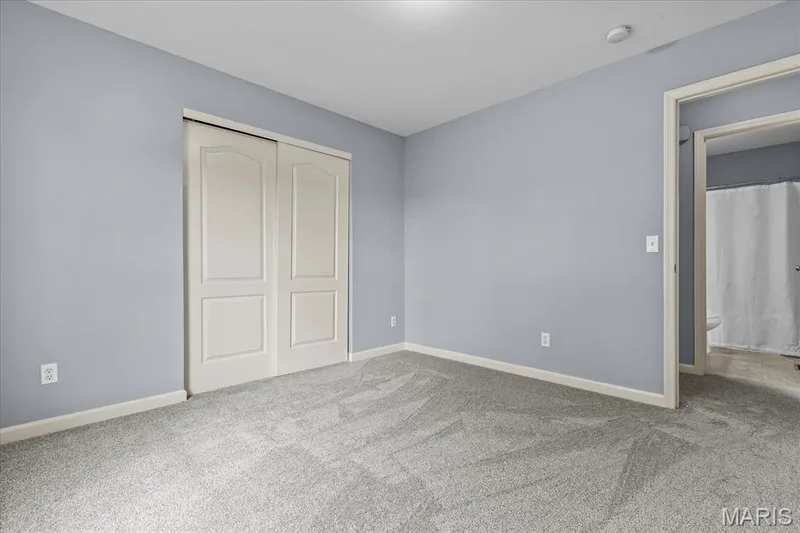Carpeted room featuring light gray walls, white trim, and a built-in closet with double bifold doors — 521 Cimarron Woods Court, Wentzville, MO 63385