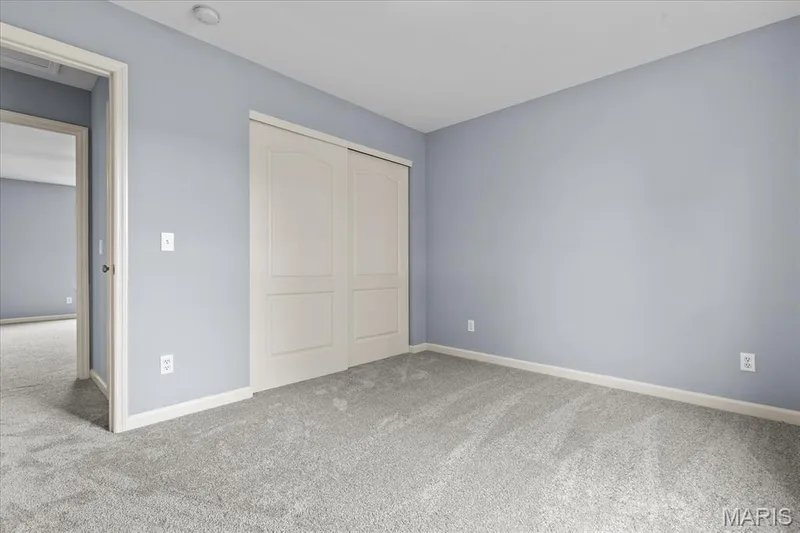 Grey textured carpeting, light blue wall paint, white trim, and white bi-fold closet doors — 521 Cimarron Woods Court, Wentzville, MO 63385