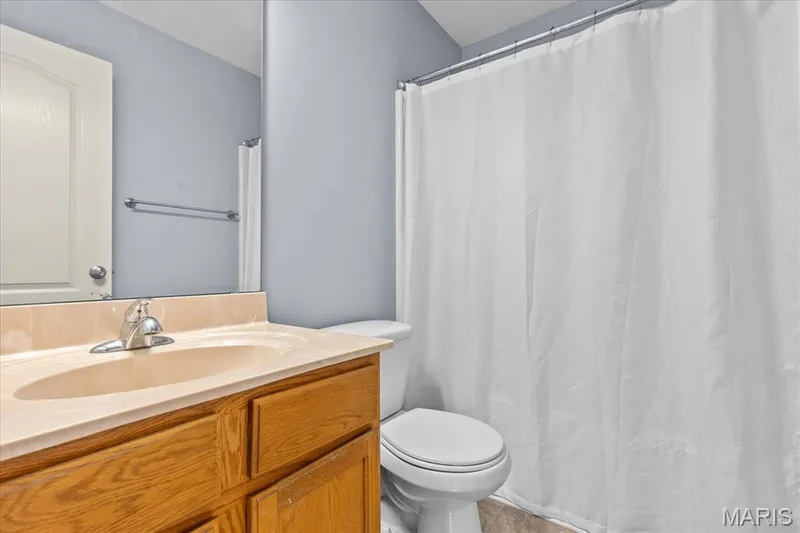 Bathroom featuring a single vanity with an integrated sink, polished chrome faucet, wood-finish cabinetry, and a toilet — 521 Cimarron Woods Court, Wentzville, MO 63385