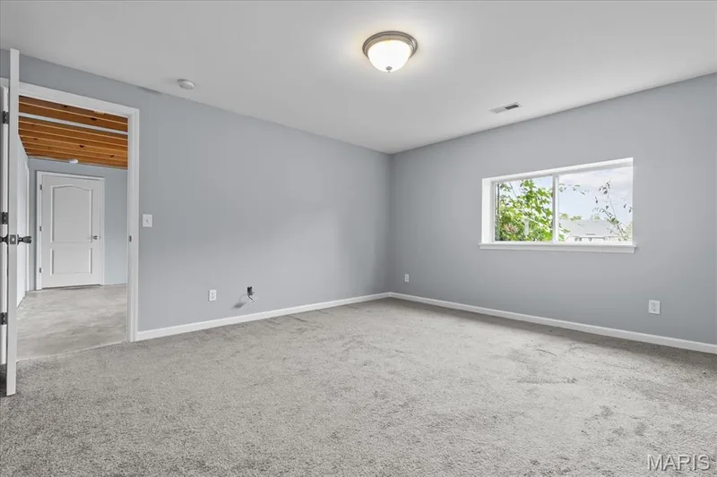 Spacious room with light gray walls, gray carpeting, and a window providing natural light — 521 Cimarron Woods Court, Wentzville, MO 63385