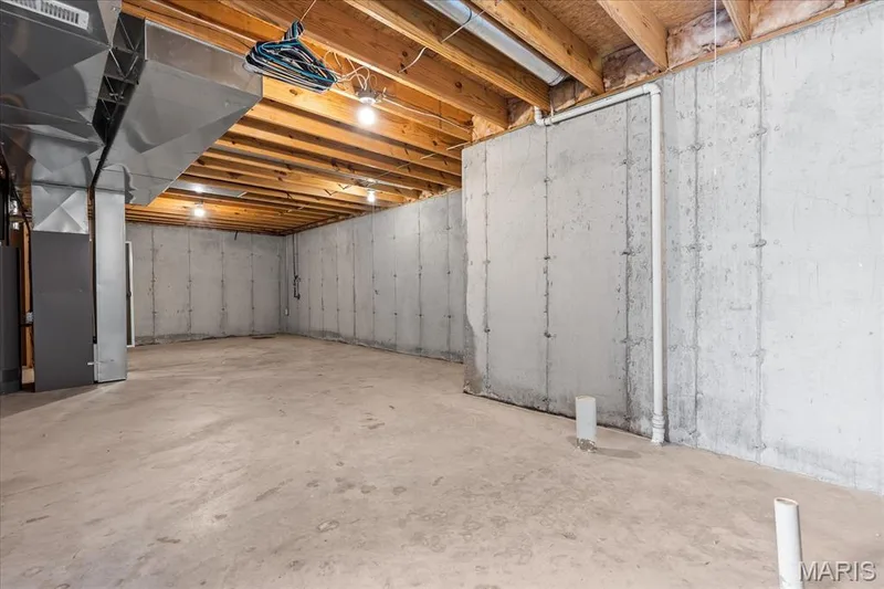 Unfinished basement with concrete walls and flooring, exposed wooden ceiling joists, and overhead lighting — 521 Cimarron Woods Court, Wentzville, MO 63385