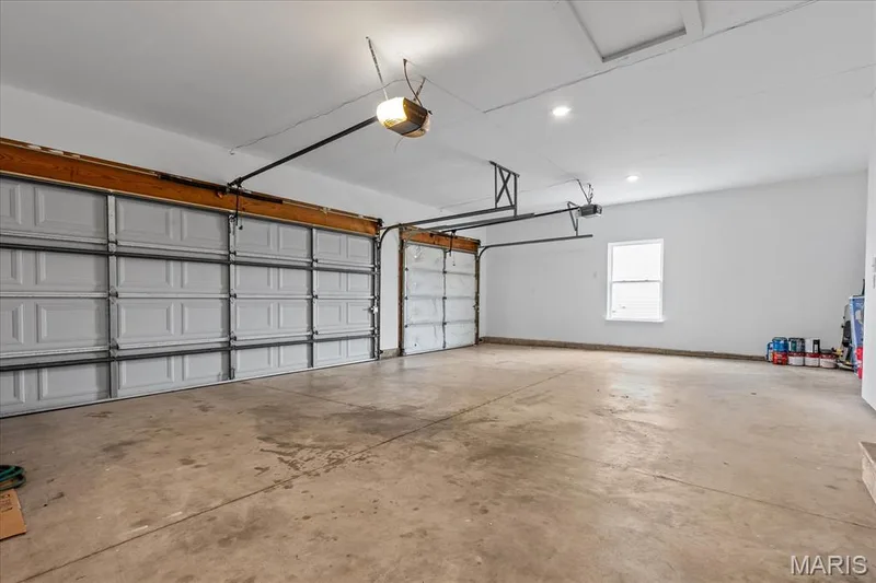Spacious garage featuring two overhead doors, a concrete floor, recessed lighting, and a single window — 521 Cimarron Woods Court, Wentzville, MO 63385