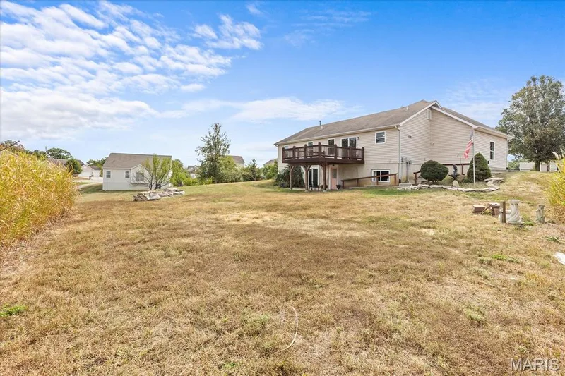 Expansive backyard with a two-story residence featuring a large elevated deck and ground-level patio access — 521 Cimarron Woods Court, Wentzville, MO 63385