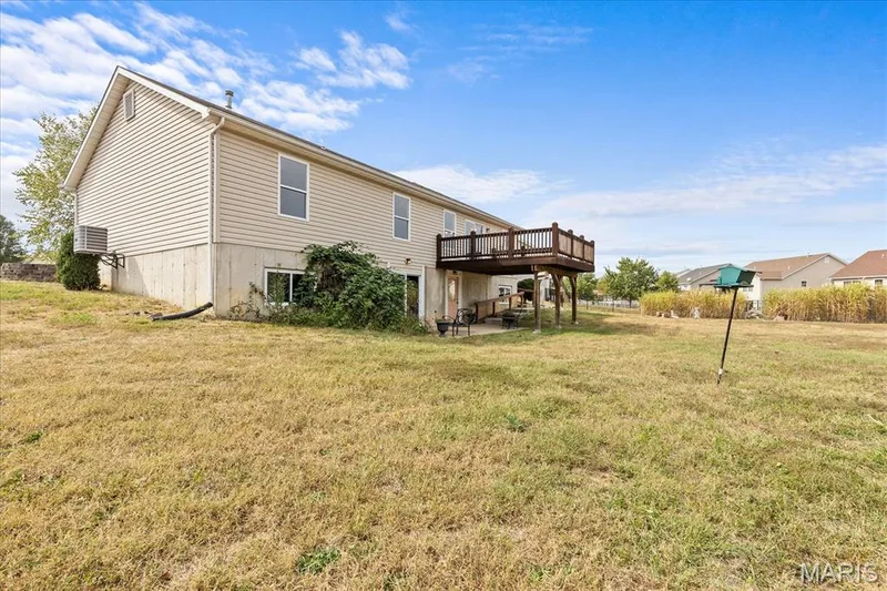Rear exterior with elevated wood deck, lower-level concrete patio, and a concrete foundation — 521 Cimarron Woods Court, Wentzville, MO 63385