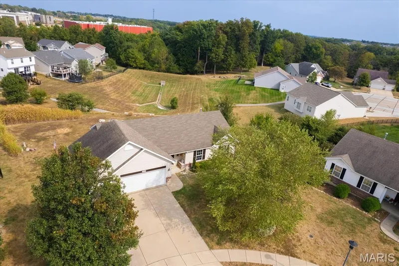 Property featuring an attached two-car garage, concrete driveway, and established trees — 521 Cimarron Woods Court, Wentzville, MO 63385